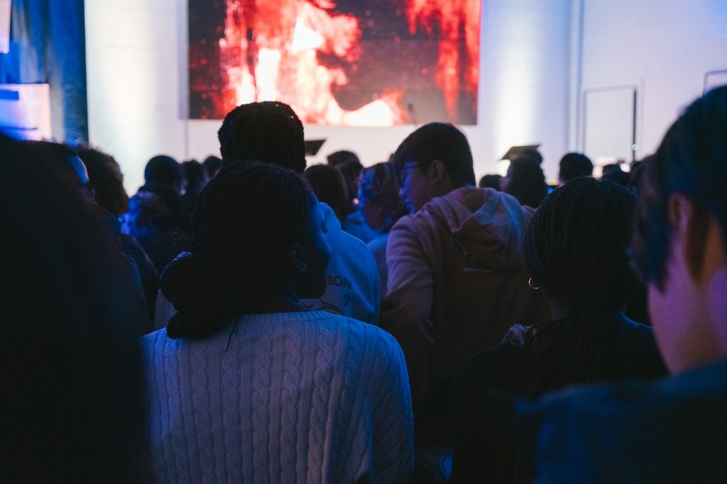 Crowd of people gathered at a live event in a modern event space with stage lighting and atmosphere